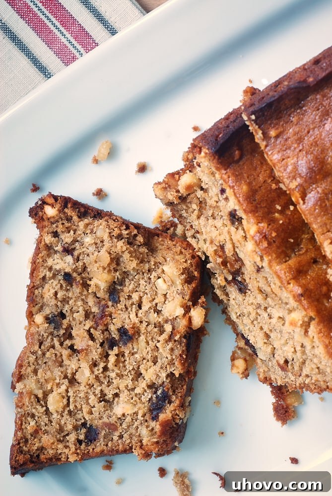 overhead view of Hazelnut Date Bread on a white plate, highlighting the golden crust and interior