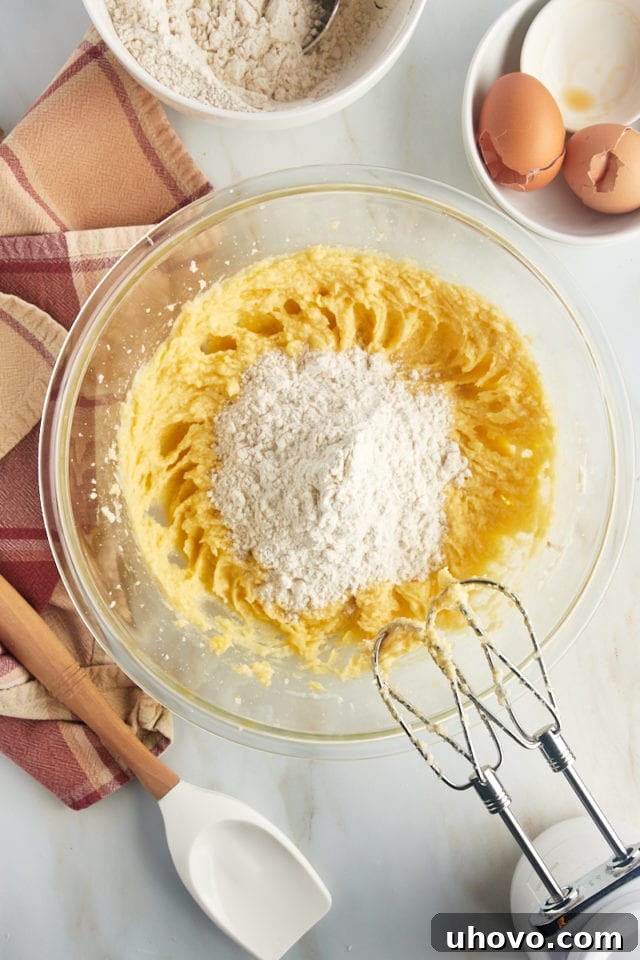 An overhead perspective shows the gradual addition of dry ingredients into the bowl of wet ingredients, illustrating the process of combining the cookie dough.