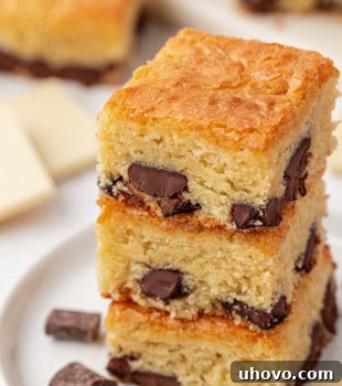 A stack of three white chocolate brownies on a white plate, showcasing their inviting texture.