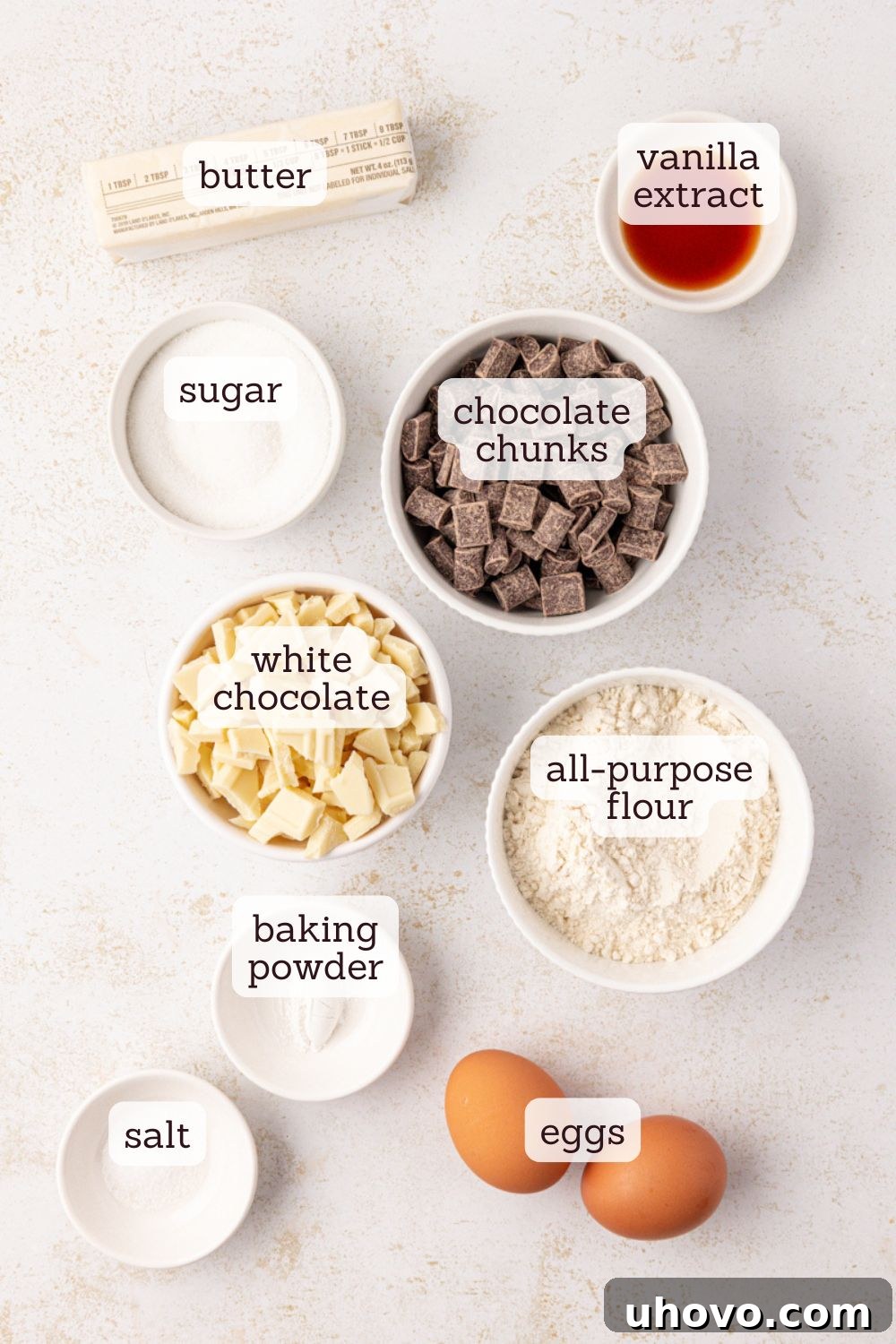 An overhead view of all the essential ingredients artfully arranged for making white chocolate brownies, including white chocolate, butter, flour, sugar, eggs, and chocolate chunks, ready for preparation.
