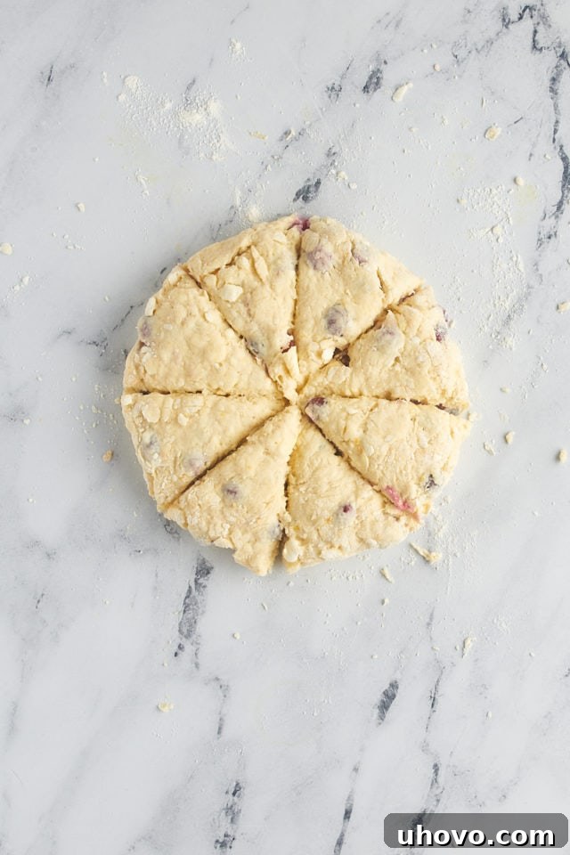 overhead view of cut cranberry orange scone dough on a marble surface