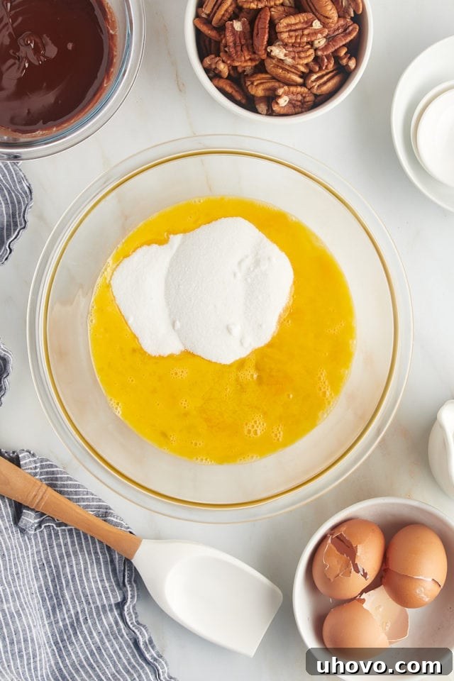 overhead view of beaten eggs, corn syrup, sugar, vanilla extract, and salt in a glass mixing bowl