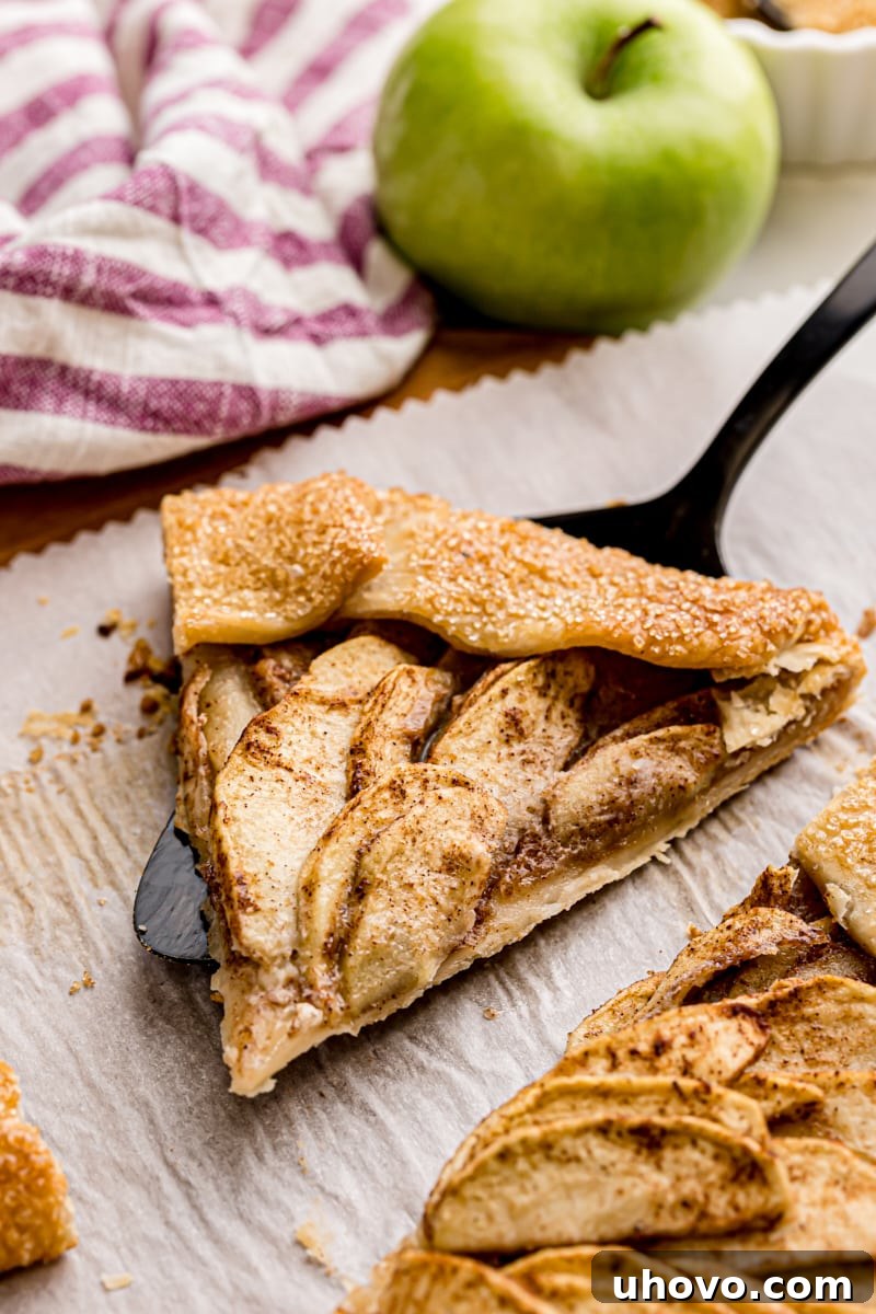 a slice of apple galette on a pie server set on parchment paper