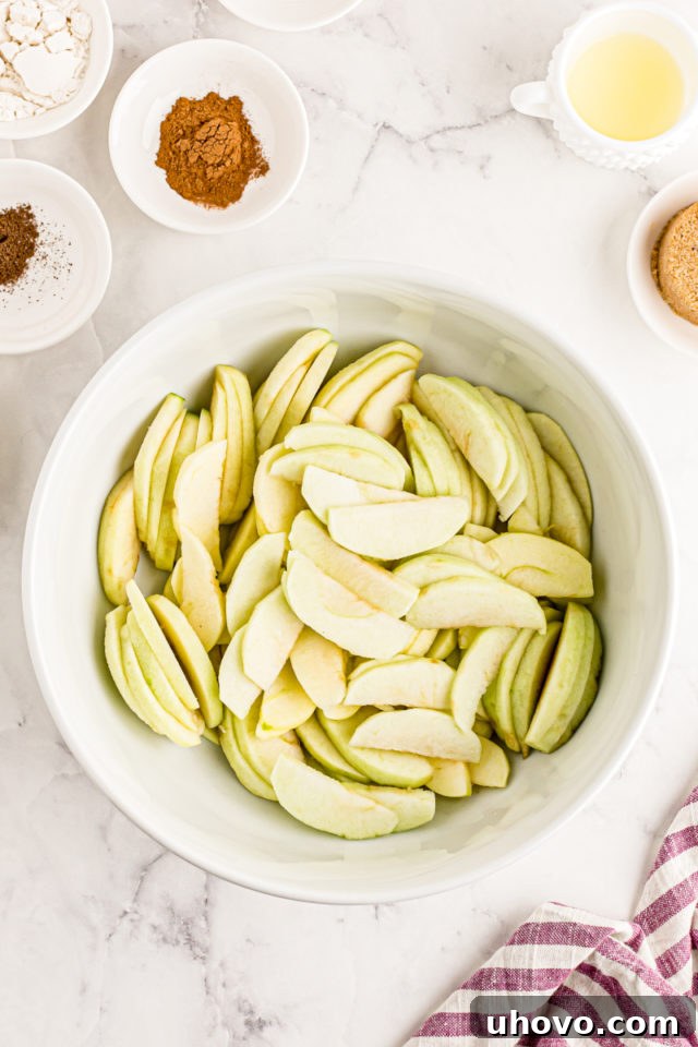 overhead view of sliced apples in a white mixing bowl
