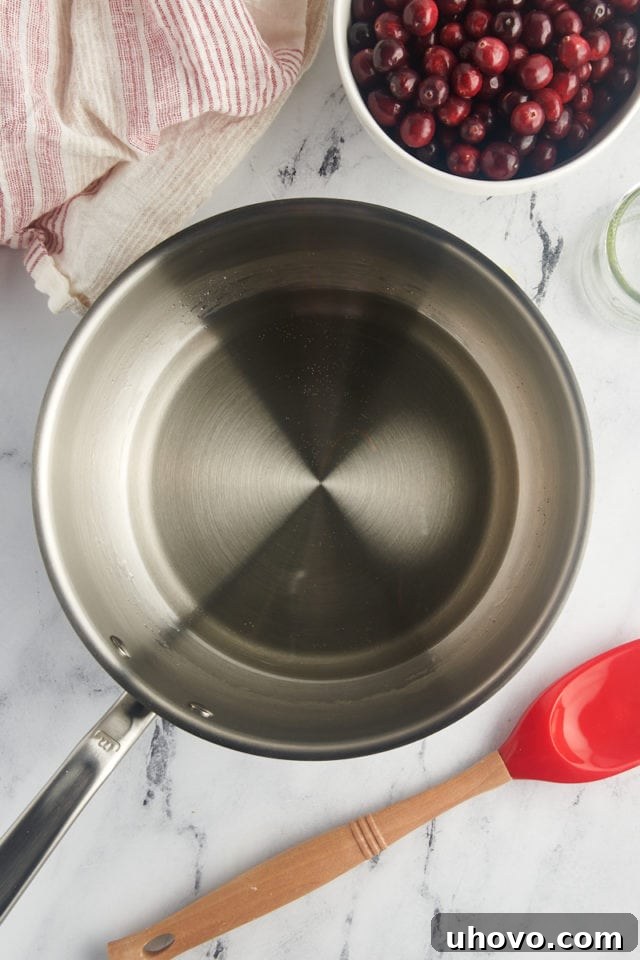 Overhead view of clear simple syrup simmering gently in a saucepan, indicating the sugar has dissolved.