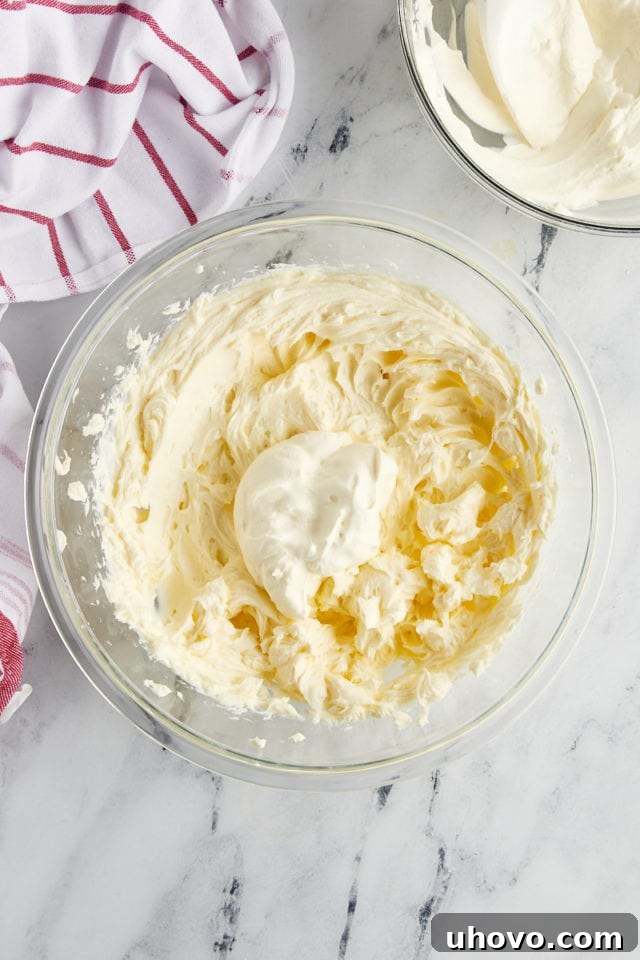 overhead view of whipped cream added to cream cheese mixture for no-bake cranberry cheesecake