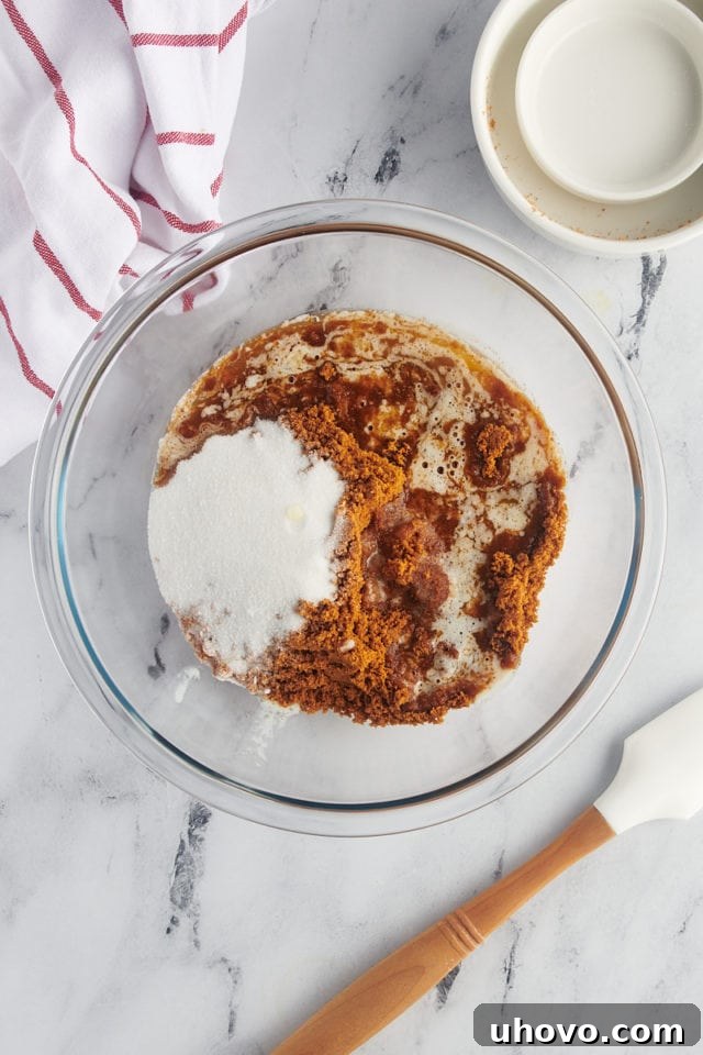 overhead view of Biscoff cookie crumbs, sugar, and melted butter in a glass mixing bowl