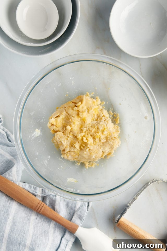 Overhead view of the tart dough after mixing, forming a cohesive ball in a glass bowl.