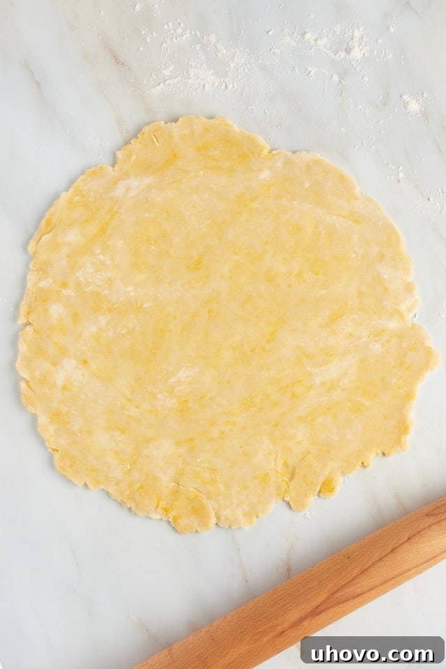 Overhead view of rolled out pastry crust on a lightly floured surface, ready for the tart pan.