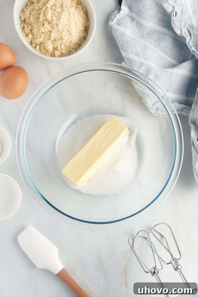Overhead view of softened butter and granulated sugar in a glass bowl, ready to be creamed for the frangipane.