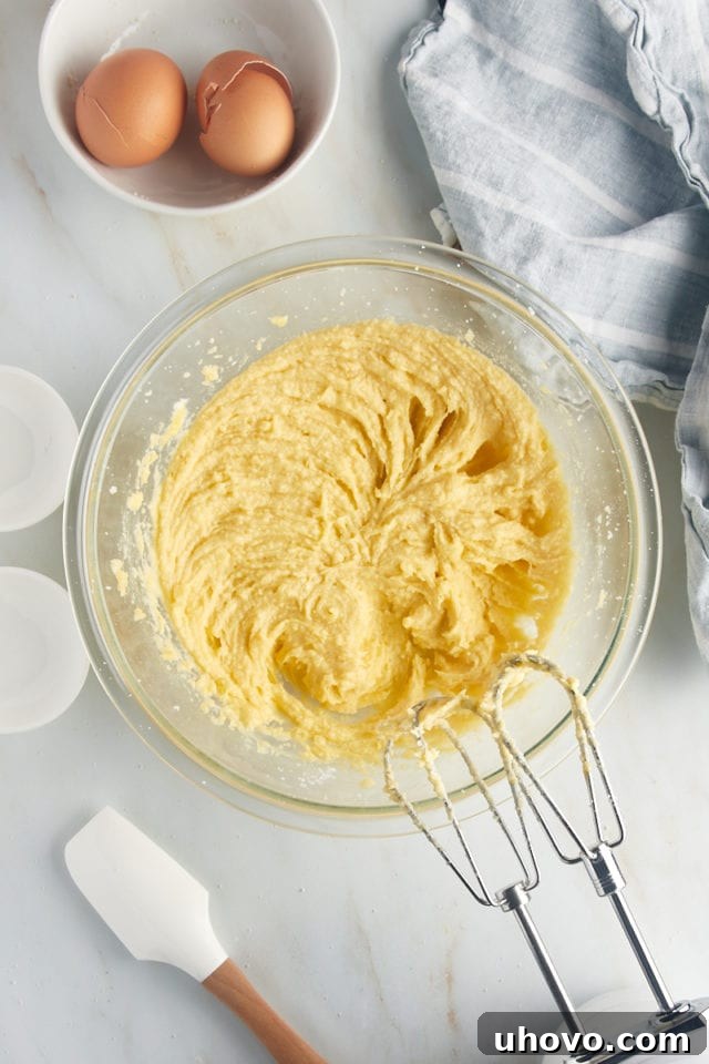 Overhead view of smooth, creamy frangipane filling in a glass bowl with electric mixer beaters resting inside.