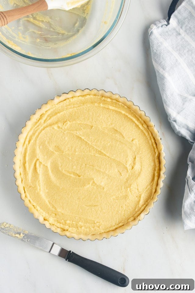 Overhead view of the smooth frangipane filling evenly spread onto the chilled tart crust in the pan.