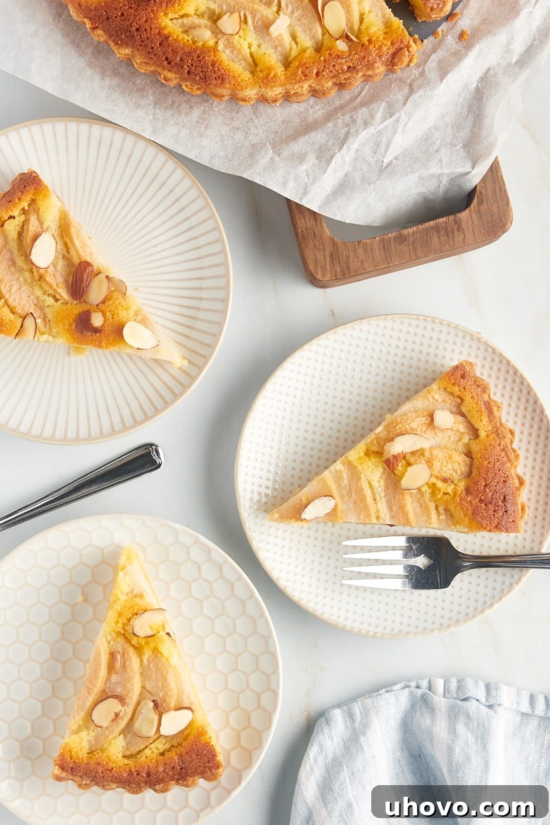 Three individual plates, each holding a perfectly baked slice of pear frangipane tart, ready to be enjoyed as a gourmet dessert.