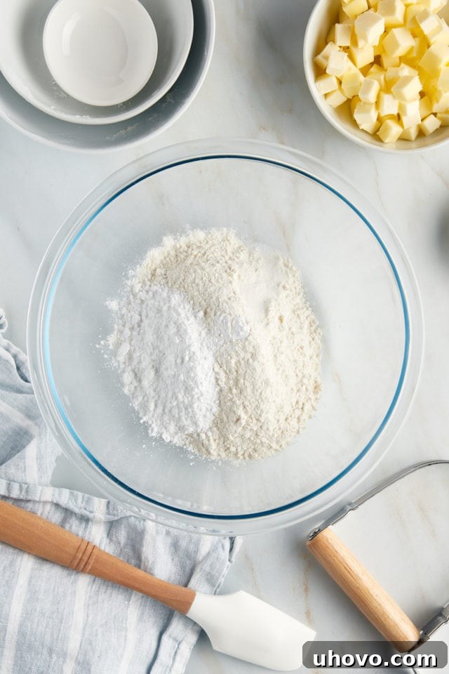 Overhead view of dry ingredients for crust (flour, confectioners' sugar, salt) in a glass bowl before mixing.