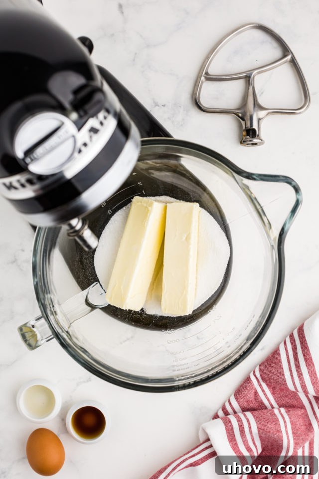 An overhead view of unsalted butter and granulated sugar ready in the bowl of a stand mixer, perfectly softened for creaming.