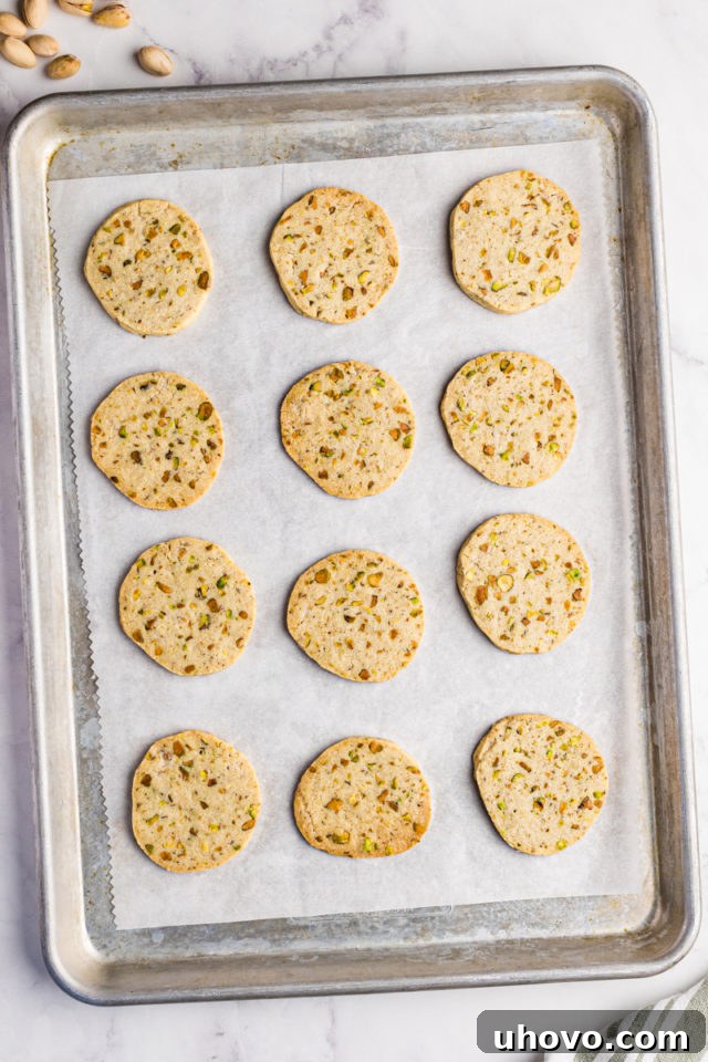 overhead view of freshly baked pistachio cookies on a parchment-lined baking sheet
