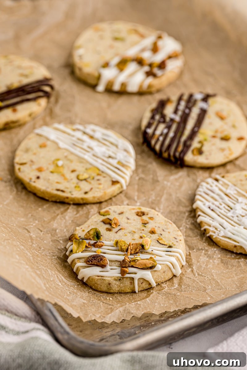 pistachio cookies topped with drizzles of dark and white chocolate and topped with sea salt and chopped pistachios