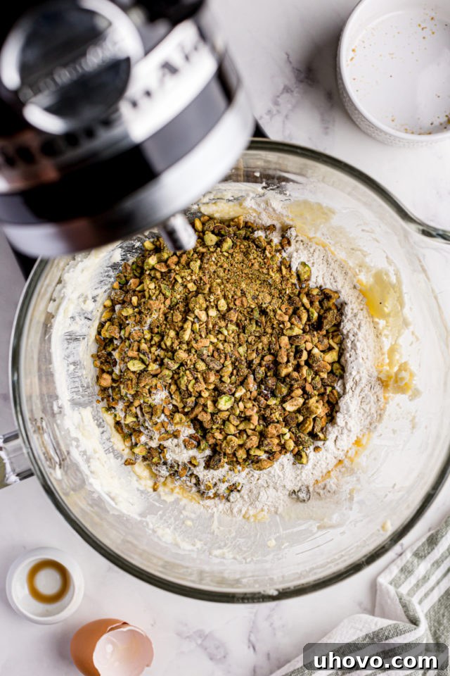 overhead view of flour and chopped pistachios added to cookie dough