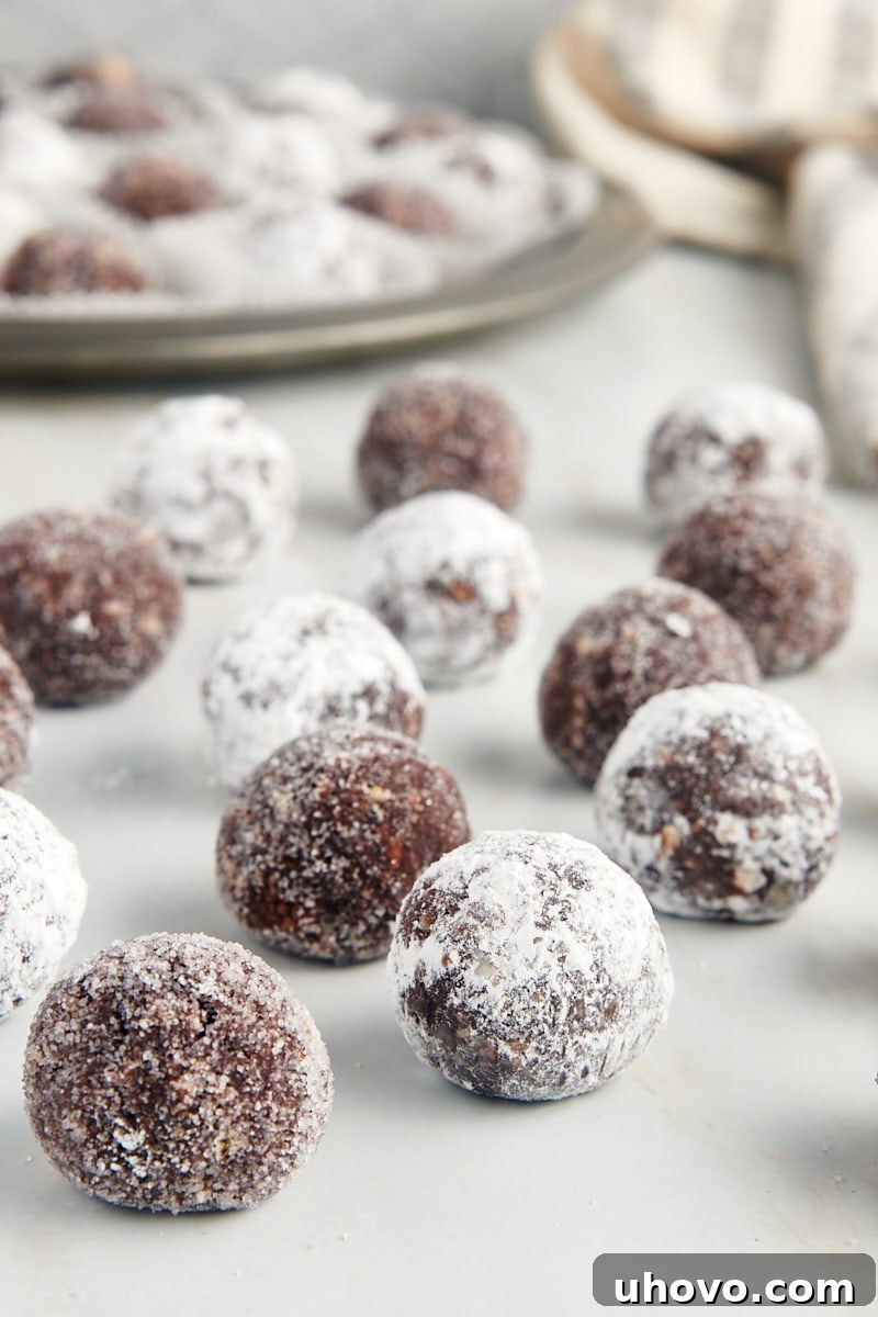bourbon balls on a marble countertop with more on a pewter tray in the background
