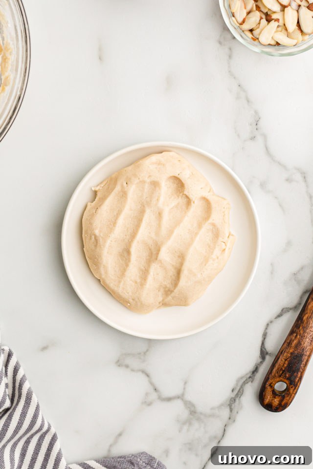Overhead view of a portion of crostata dough reserved on a small plate, covered with plastic wrap and ready for chilling to be used as a topping.