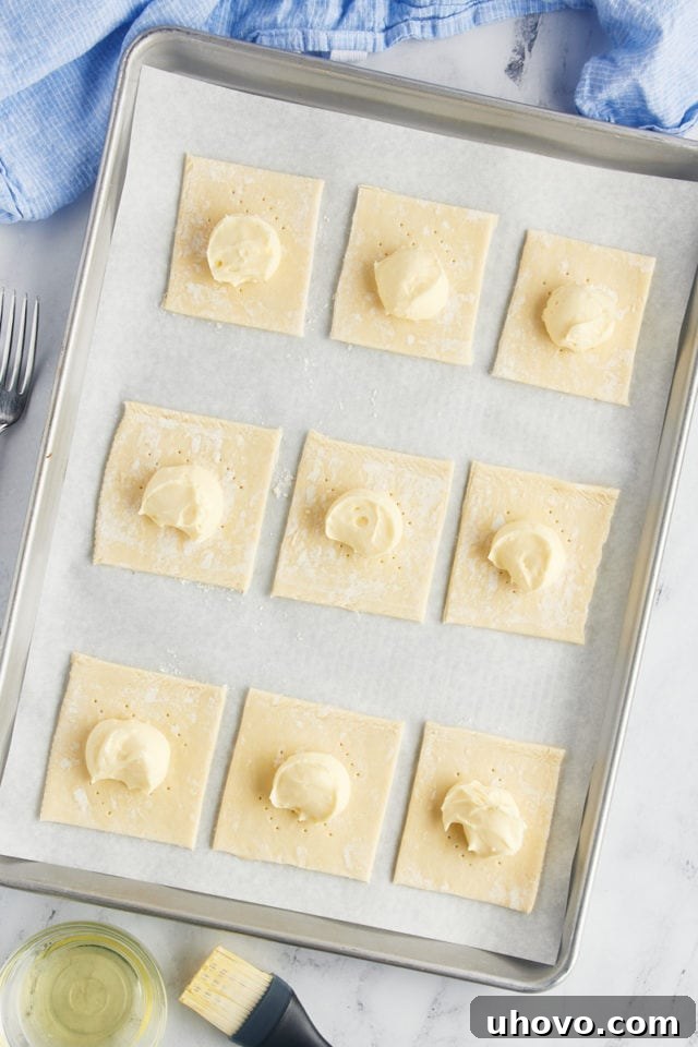 Overhead view of unbaked cheese danishes on sheet pan