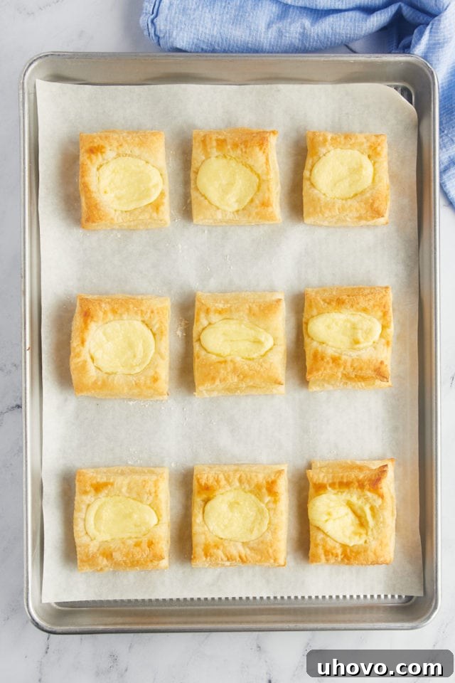 Overhead view of baked cheese danishes on sheet pan