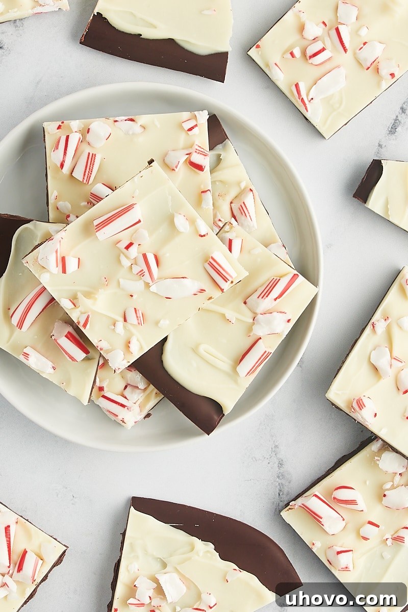 An overhead view of peppermint bark piled high on a white plate, surrounded by more pieces, creating an abundant display.