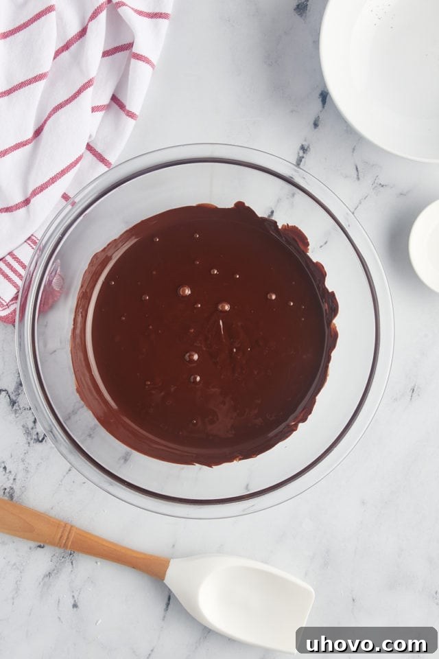 Overhead view of smooth, melted dark chocolate in a glass mixing bowl after thorough stirring.