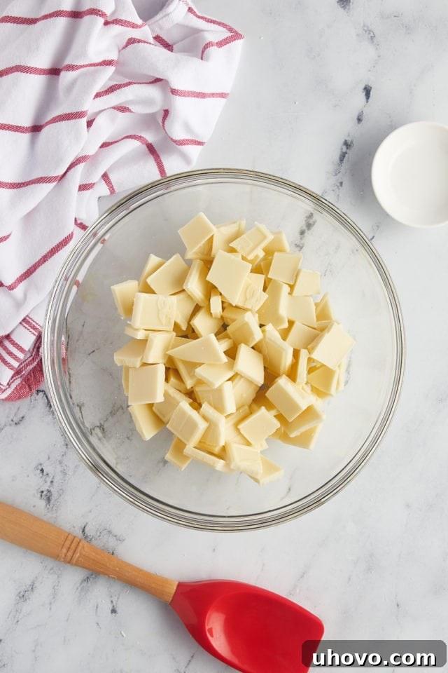 Overhead view of chopped white chocolate pieces in a glass mixing bowl, ready for melting.