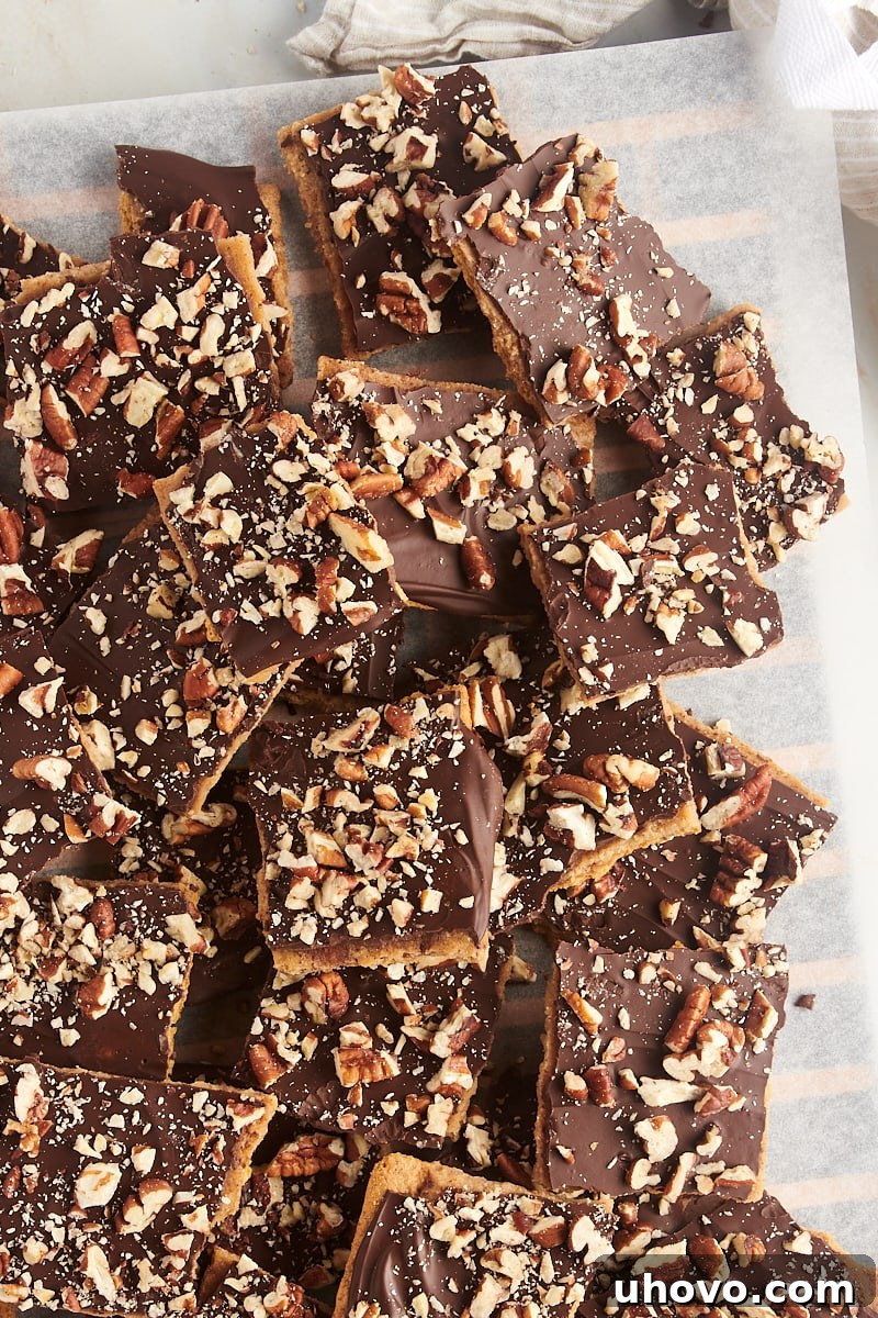 A generous pile of Graham Cracker Toffee pieces on a sheet of parchment paper, showcasing the golden toffee and chocolate layers.