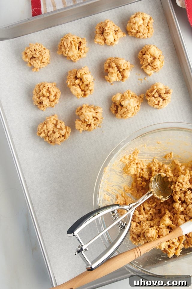 overhead view of avalanche cookies being scooped onto a parchment-lined baking sheet