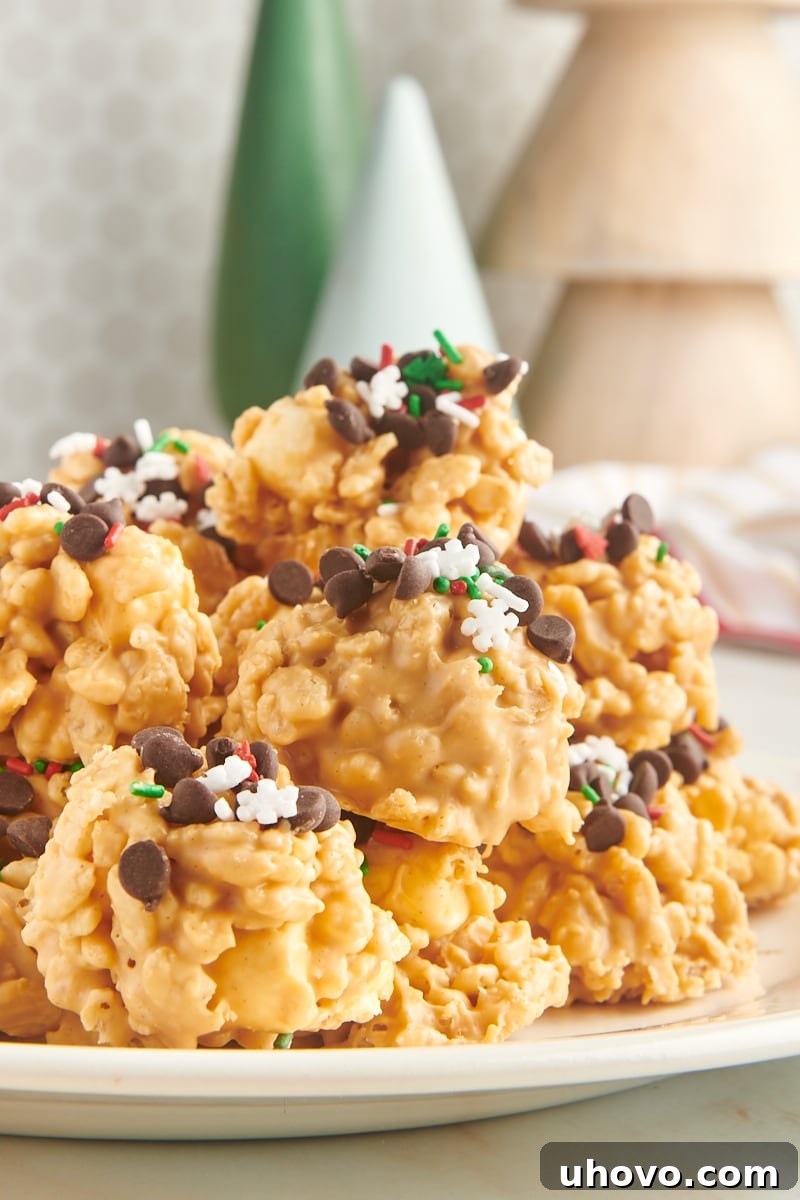 avalanche cookies piled on a white plate with small wooden Christmas trees in the background