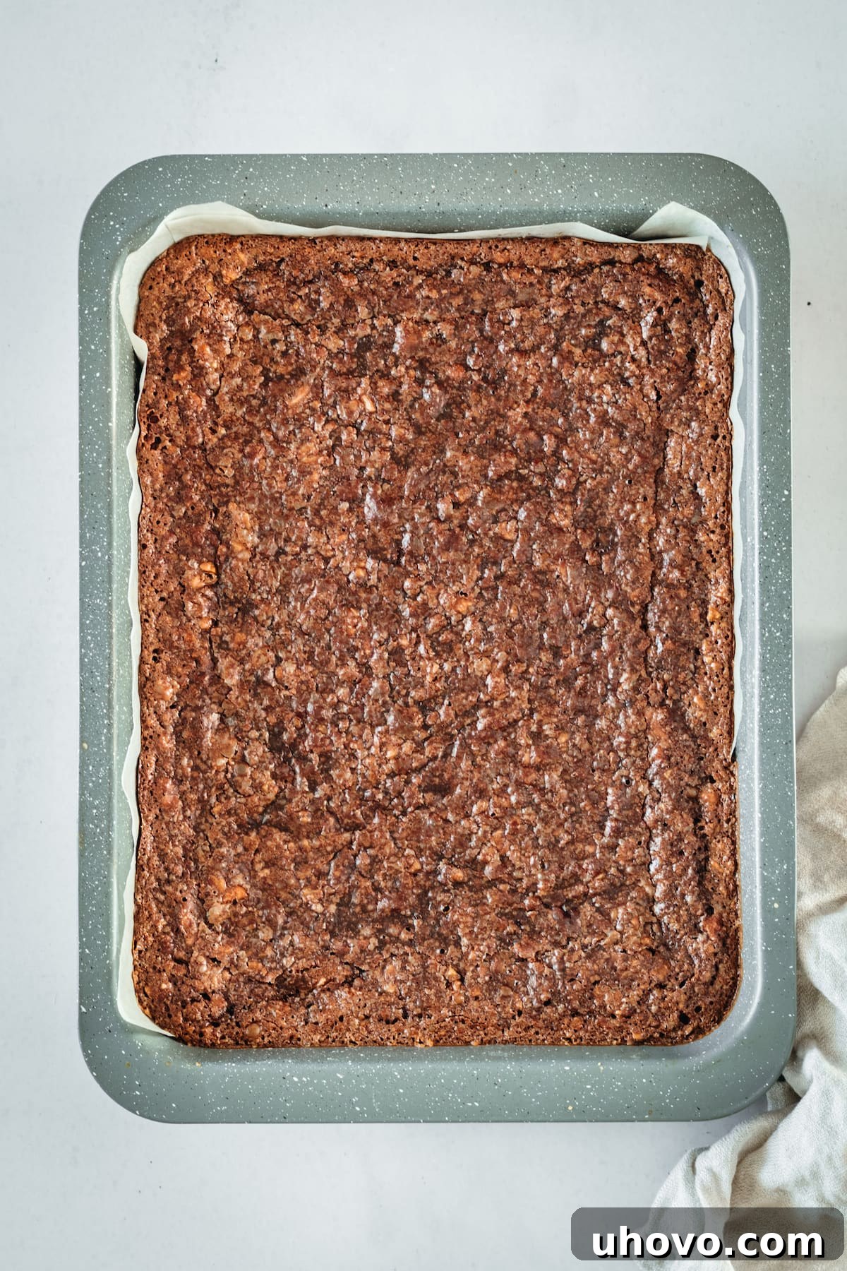 Overhead view of chocolate pecan pie bars in parchment lined baking pan