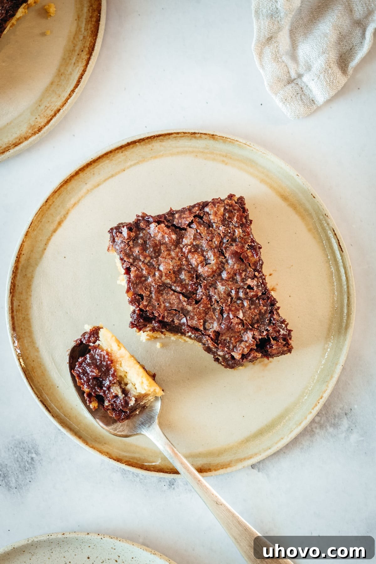 Overhead view of a plated chocolate pecan pie bar with a bite on a spoon