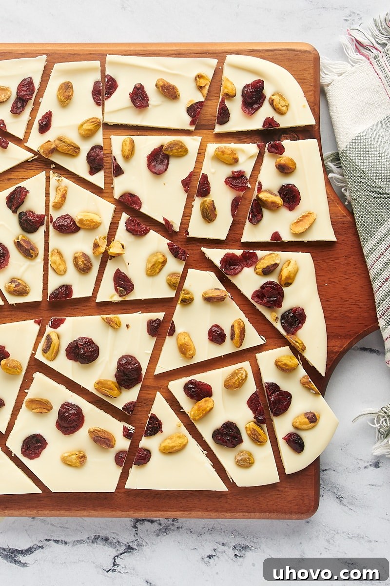 overhead view of cranberry pistachio bark perfectly cut into various sized pieces on a rustic wooden cutting board, highlighting the clean breaks