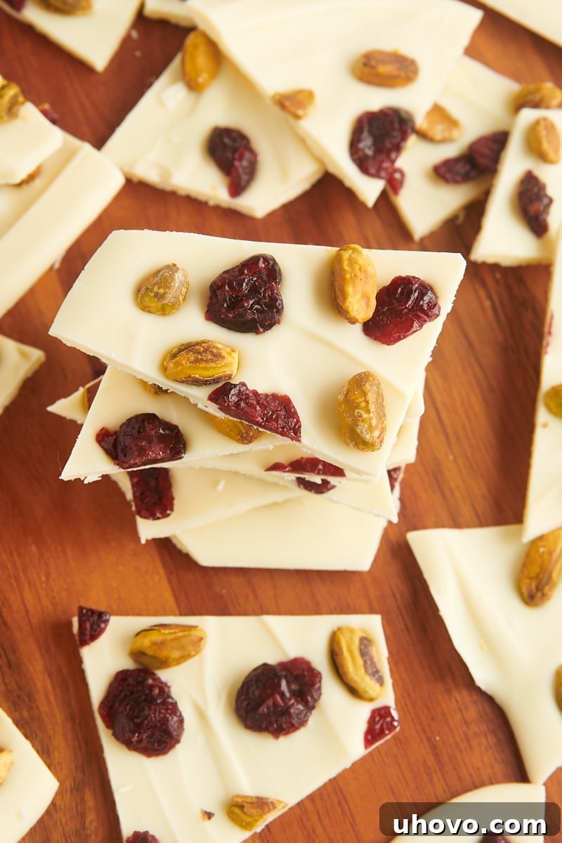 a beautifully arranged stack of cranberry pistachio bark pieces, surrounded by more bark, on a wooden surface, ready for serving or gifting