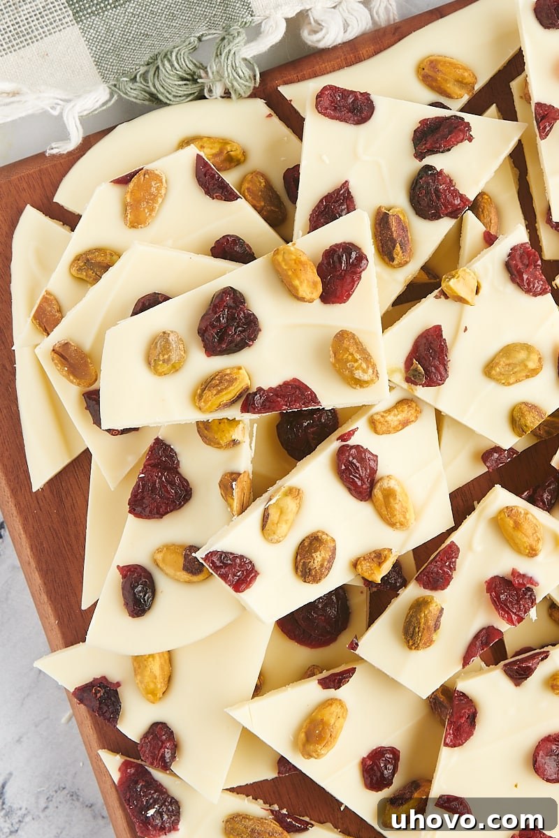 overhead view of a large pile of cranberry pistachio bark pieces on a wooden cutting board, emphasizing the bountiful nature of the treat