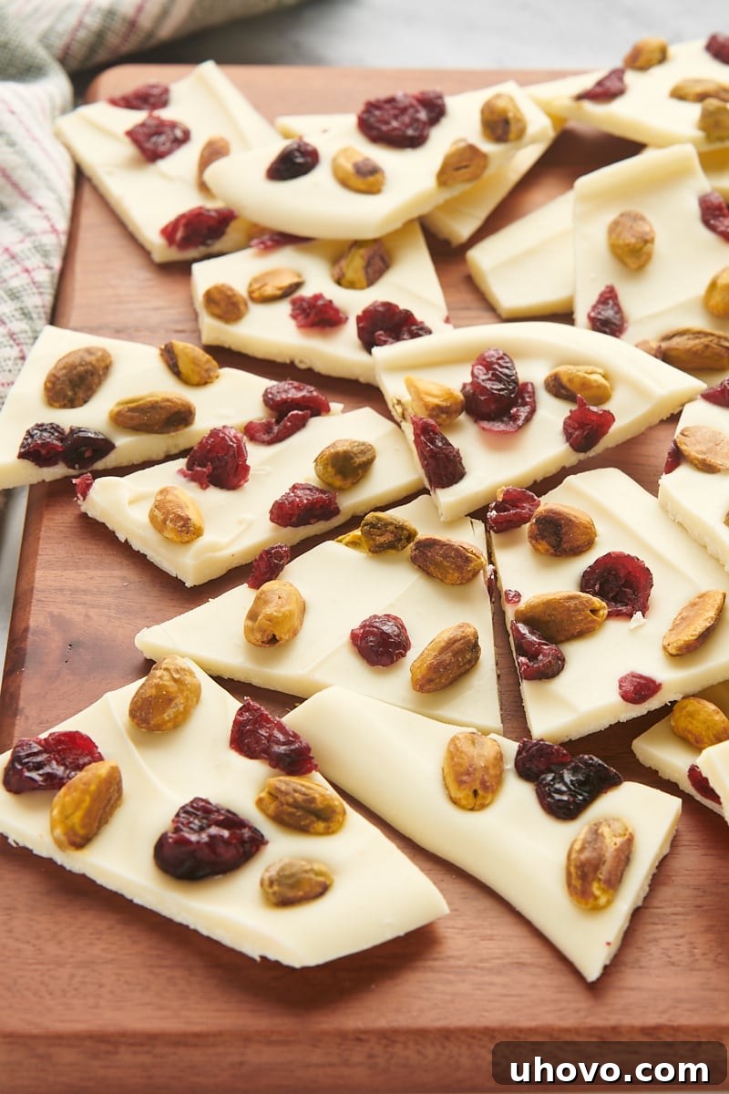 cranberry pistachio bark scattered generously on a rustic wooden cutting board, ready to be broken into pieces