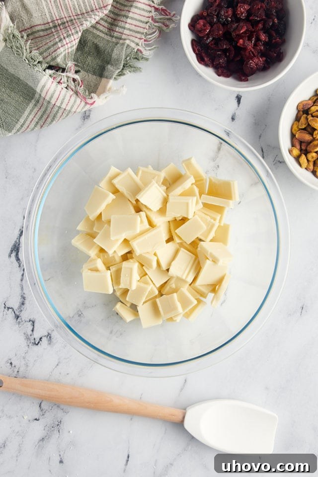 overhead view of roughly chopped white chocolate in a clear glass bowl, ready for melting