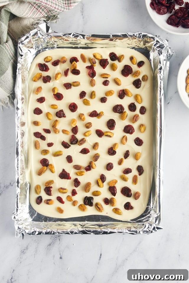 overhead view of the white chocolate cranberry pistachio bark, fully assembled with toppings, ready to be refrigerated for setting