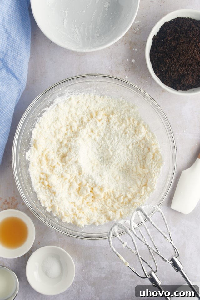 Overhead view of powdered sugar being slowly added to the creamed butter for the frosting.