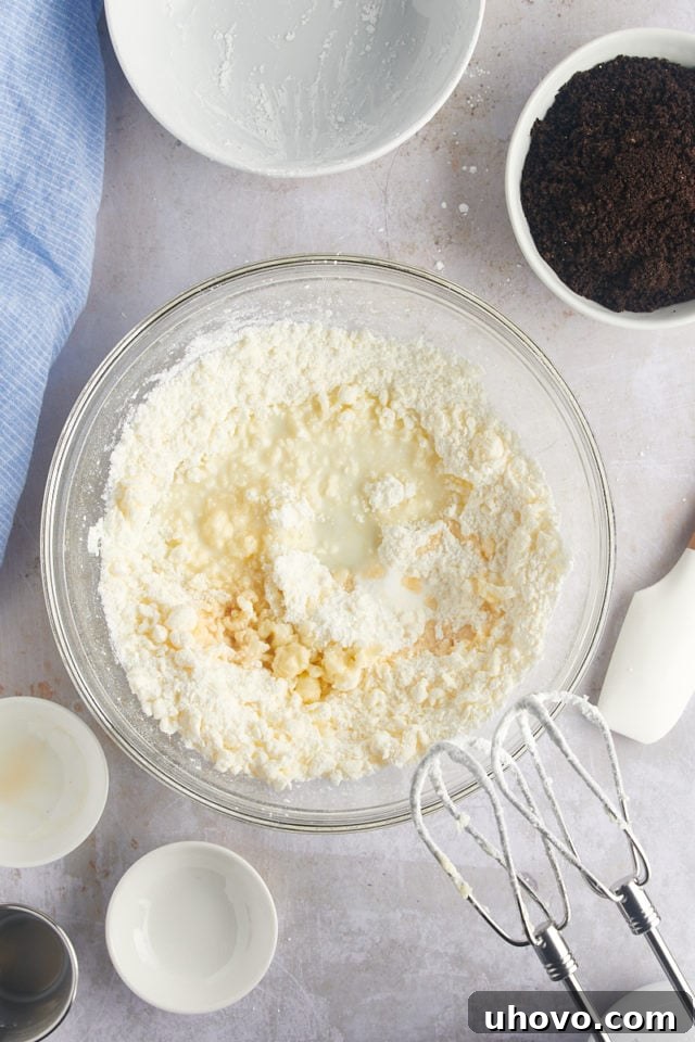 Overhead view of milk, vanilla, and salt added to the powdered sugar and butter mixture for the frosting.