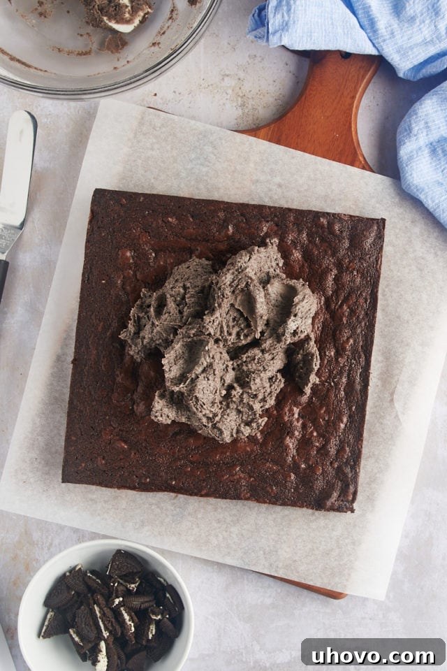 Overhead view of the fluffy Oreo frosting being generously spread onto the cooled brownies.