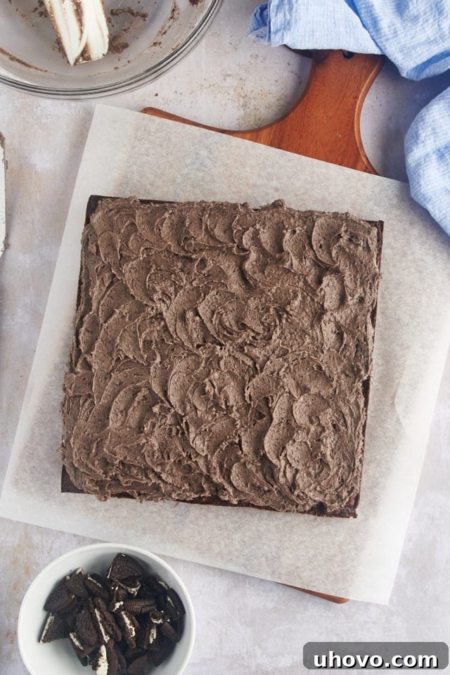 Overhead view of beautifully frosted Oreo brownies on parchment paper, ready for cutting.