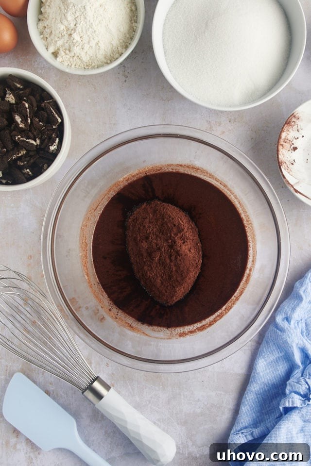 Overhead view of cocoa powder being added to the melted butter and chocolate mixture.