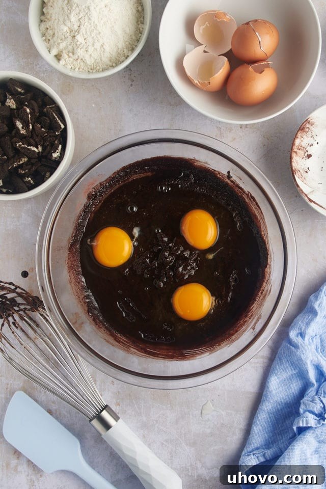 Overhead view of three large eggs cracked into a bowl, ready to be incorporated into the brownie mixture.