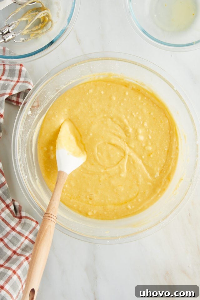 Overhead view of the fully mixed orange pound cake batter in a clear glass mixing bowl, smooth and ready for baking.