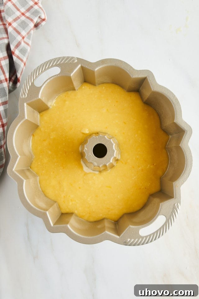 Overhead view of smooth orange pound cake batter evenly spread within a Bundt pan, ready for the oven.