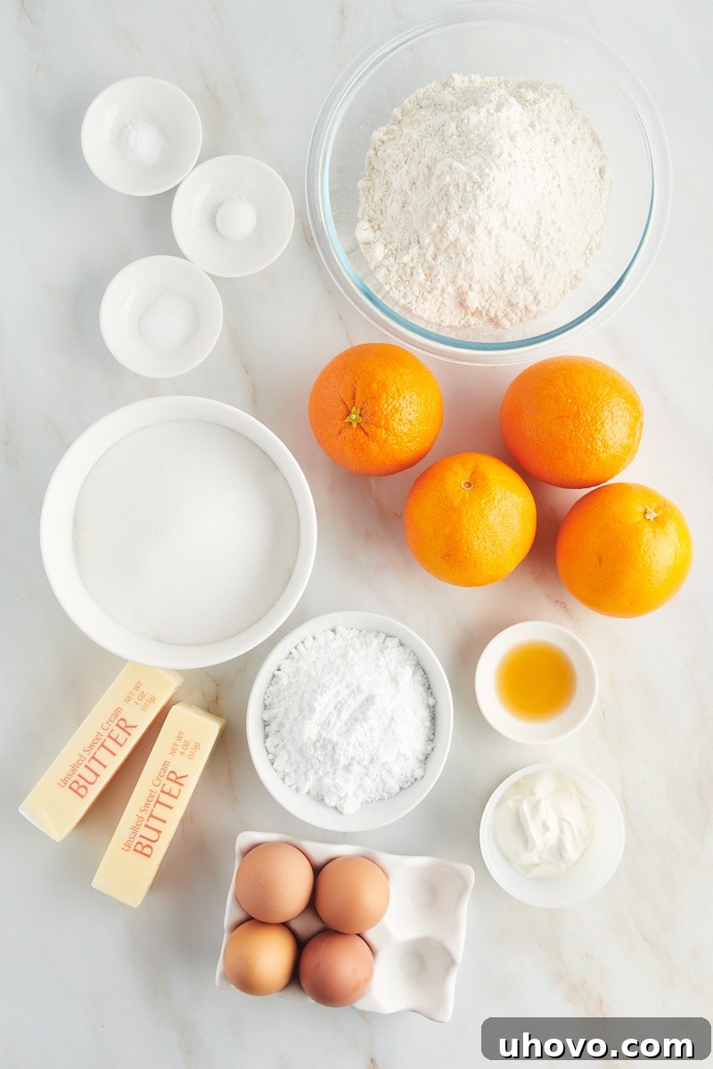 An overhead view of carefully laid out ingredients for an orange pound cake, including flour, sugar, butter, and fresh oranges.