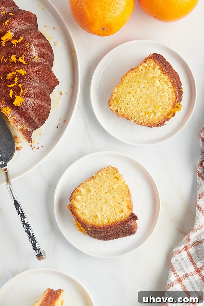 An overhead shot showcasing two perfect slices of orange pound cake on elegant white plates, ready to be enjoyed.